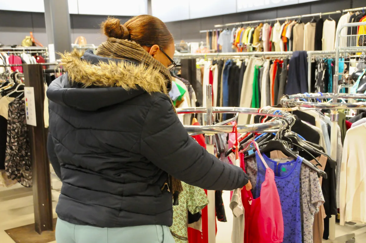 Die luftig angeordneten Kleider laden zum Shoppen ein. Man sieht eine Frau, die Kleider durchstöbert.